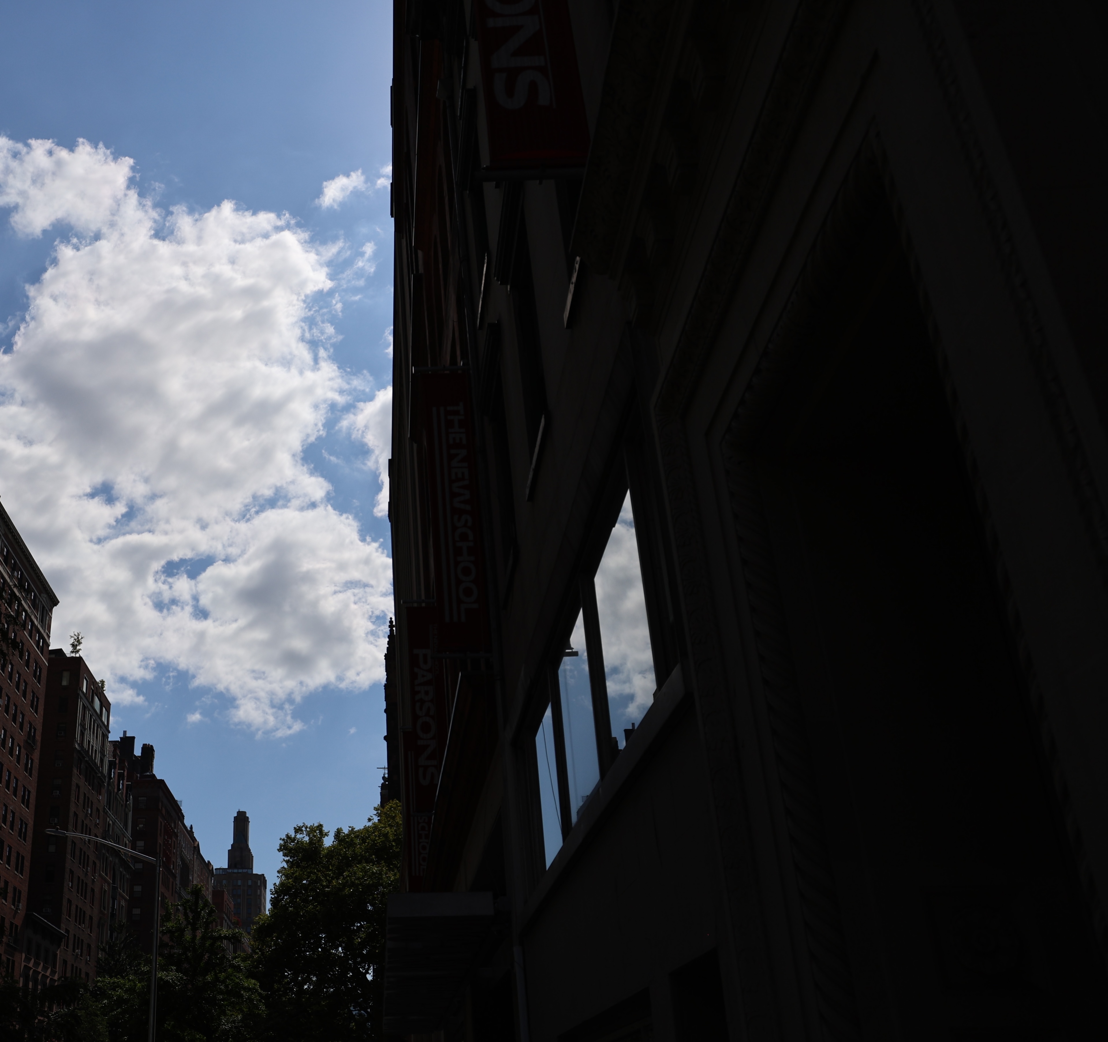 Tall buildings and bright clouds divided by a dark urban shadow