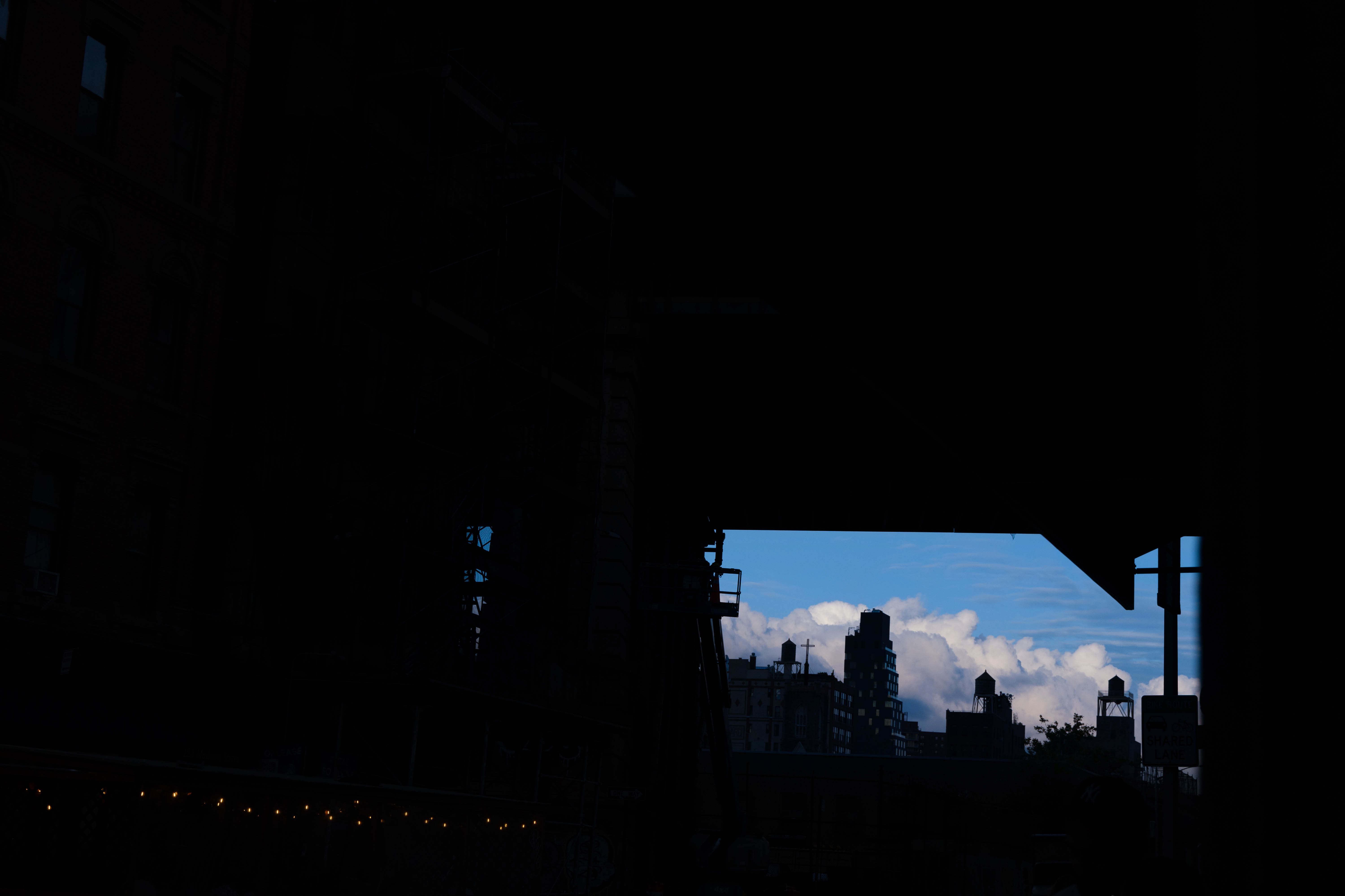 Underexposed New York street scene framing a bright blue sky and distant buildings